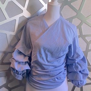 Medium sized blouse with ruffled sleeves, ties to the back. Light blue/white.